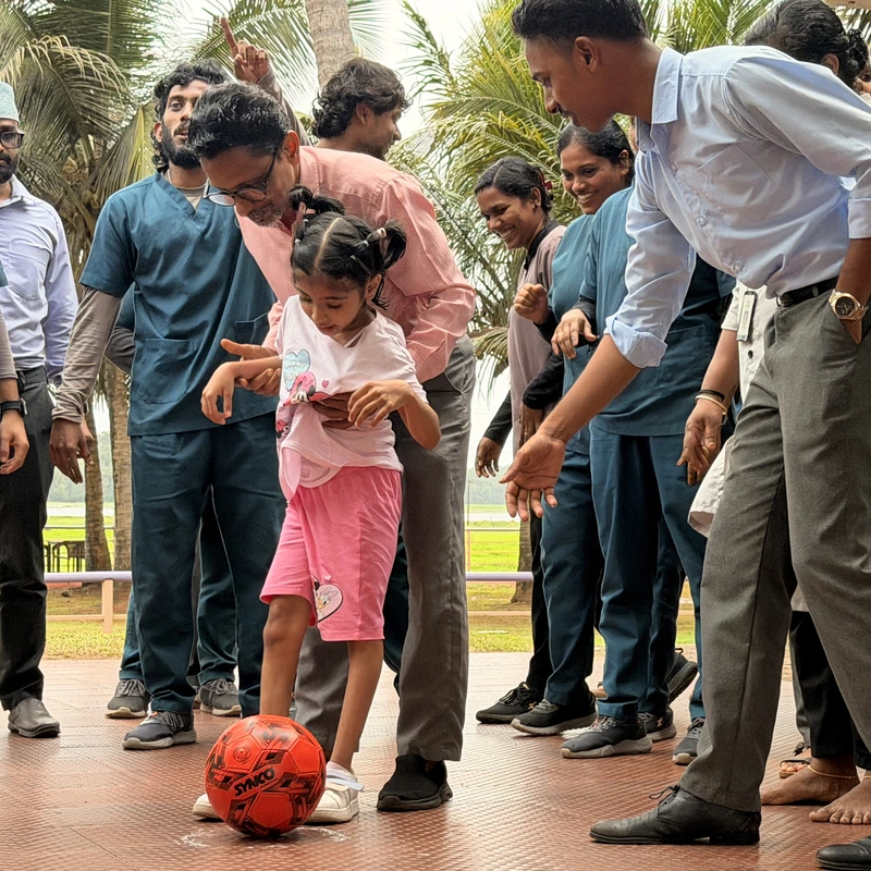 Pediatric neuro rehabilitation session with child kicking ball supported by therapists